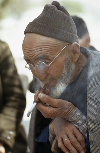 An elderly Turkish farmer smokes a cigarette.
